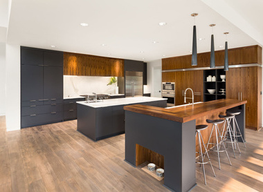 A large modern kitchen with dark cabinets and beautiful wooden worktops. 