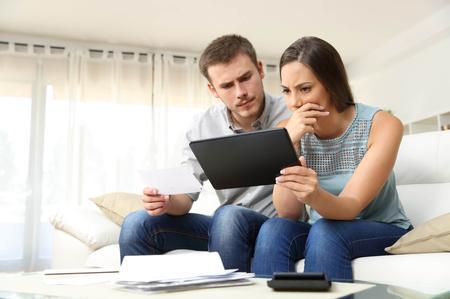 Young couple on sofa looking at iPad for building advice as their recent building work that has gone wrong.